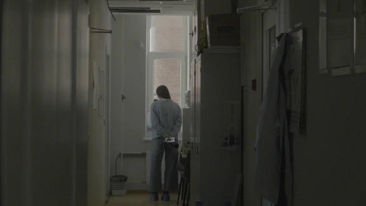 A person by a window in a corridor
